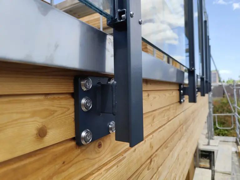 Fussplatte eines Glasgeländers, seitlich mit Schrauben an einer Holzfassade befestigt