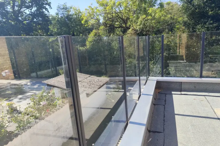 Glasgeländer Pure ohne Handlauf auf einer Dachterrasse, Blick durch das Klarglas ins Grüne